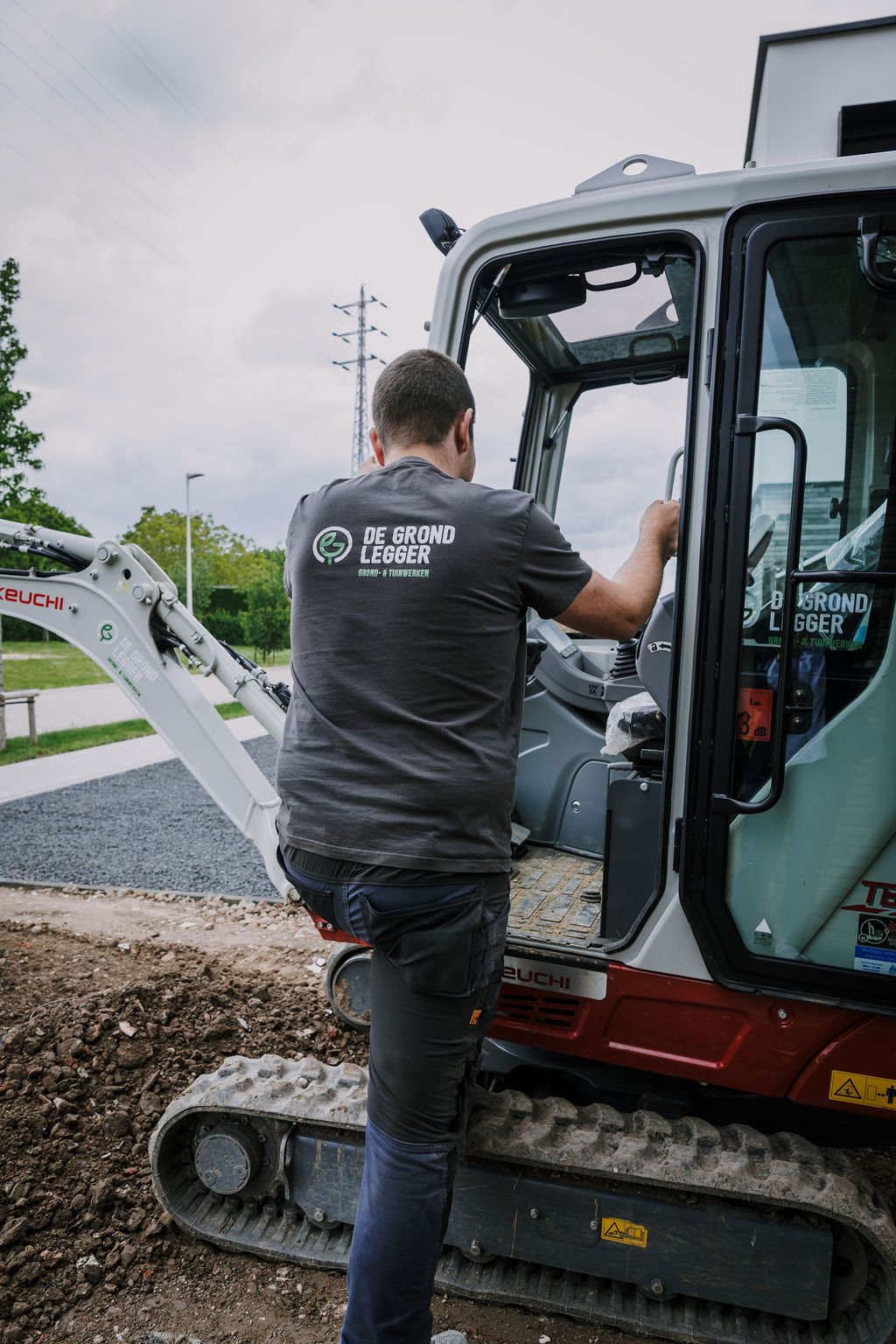 Zaakvoerder van De Grondlegger stapt in een Takeuchi-minigraver tijdens grondwerken aan een residentieel project.